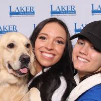 Two alumni and a dog posing together